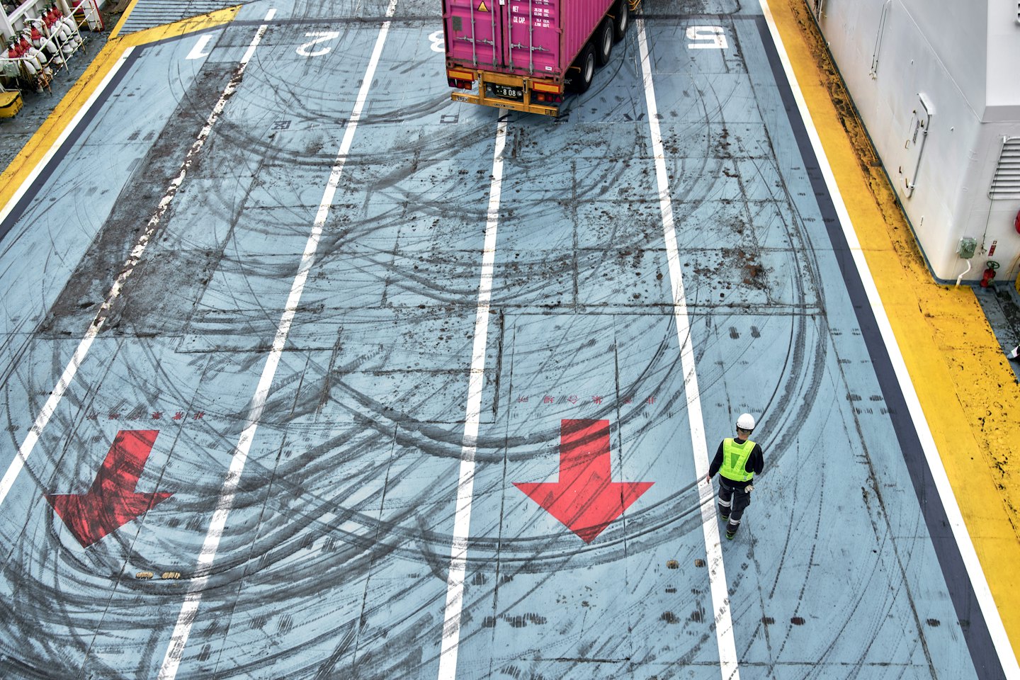 Port worker in high-visibility vest on a cargo ship deck.