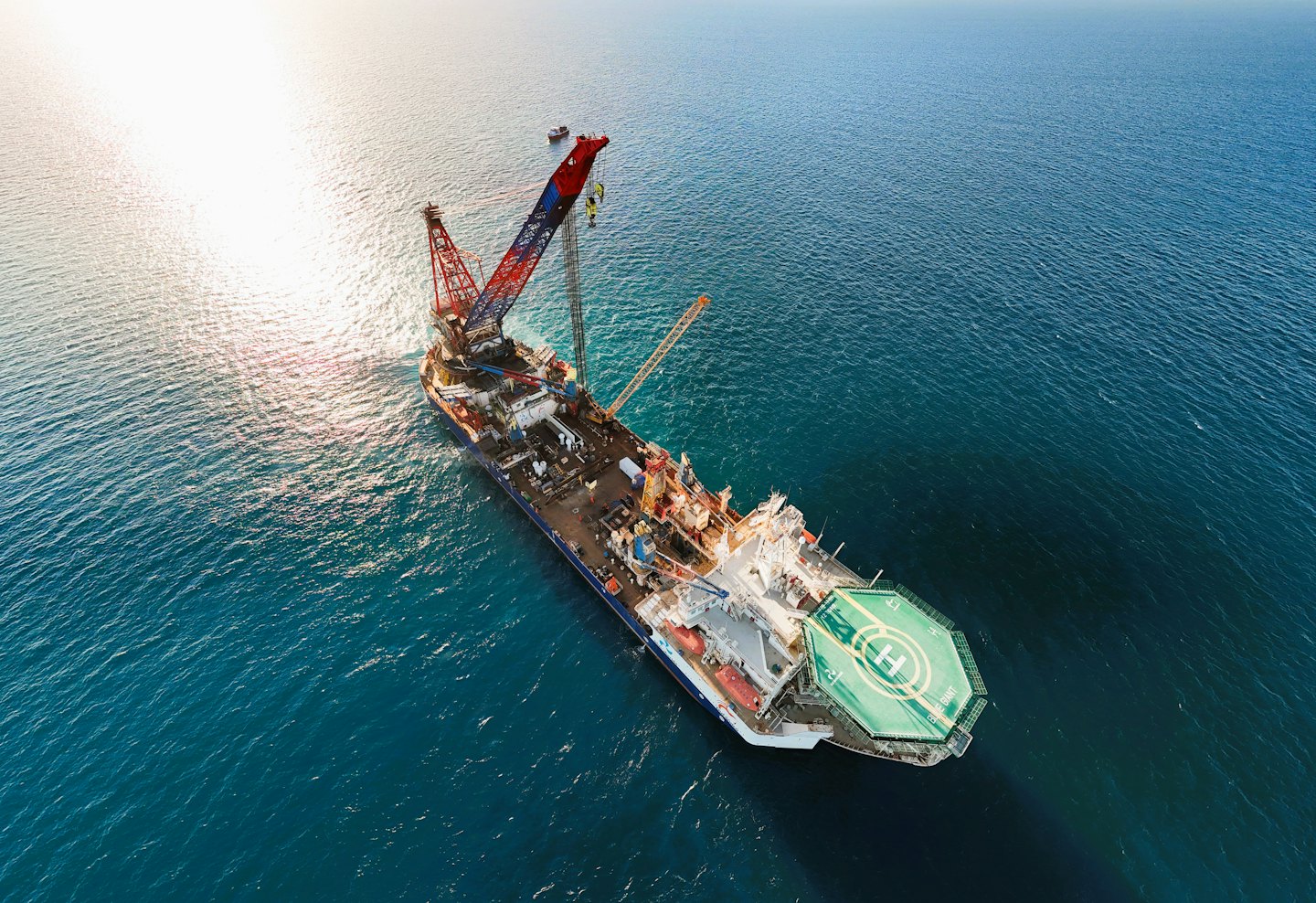 Large industrial vessel with cranes working in open water.